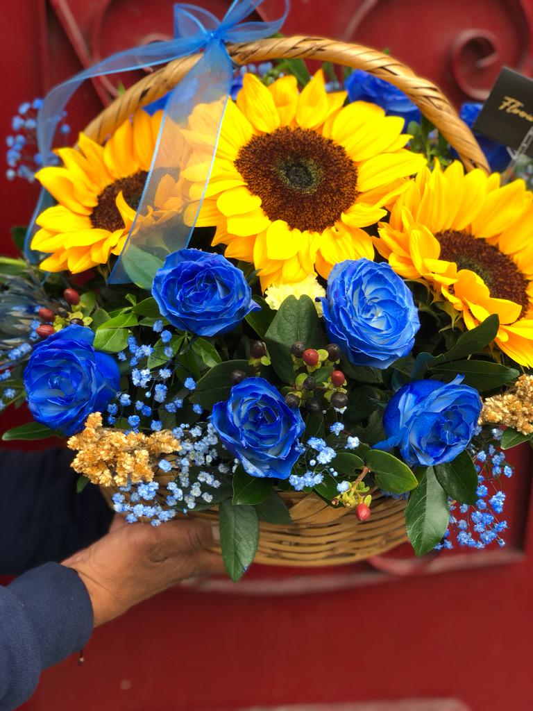 Canasta con rosas azules y girasoles